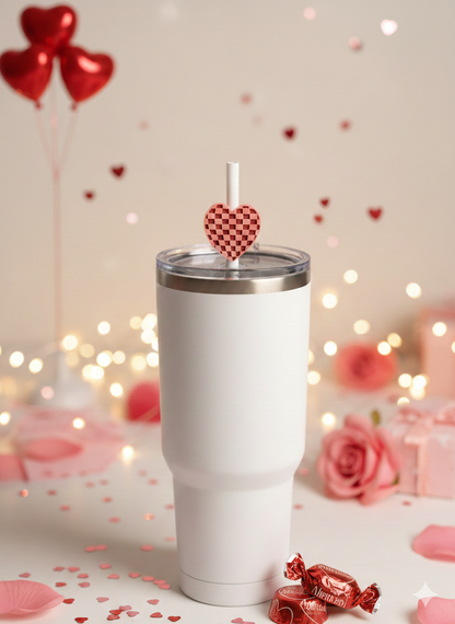 White tumbler with a heart-shaped straw on a table with Valentine's Day decorations.