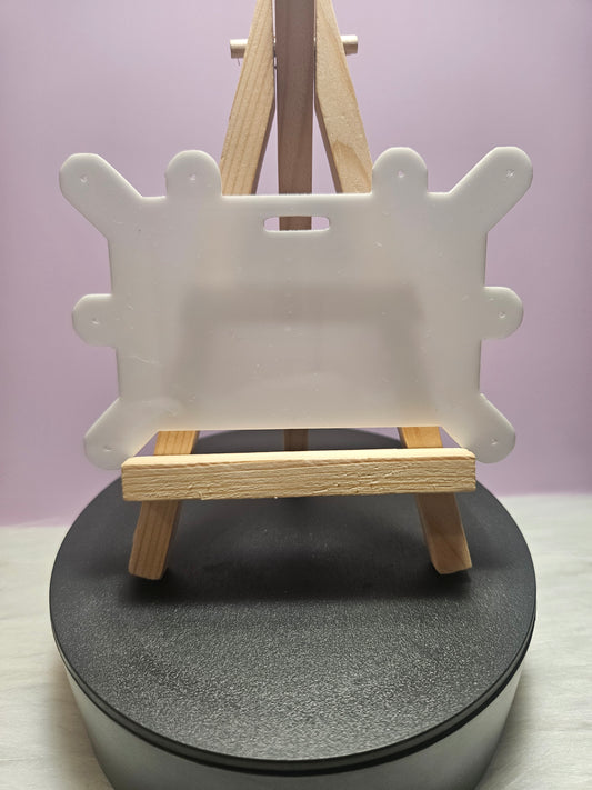 Puzzle-shaped white badge pin holder on round black stand with wooden easel clip