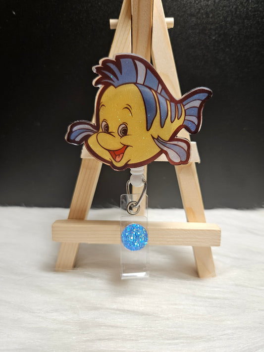 Flounder badge reel with cartoon flounder charm and blue glitter pull tag
