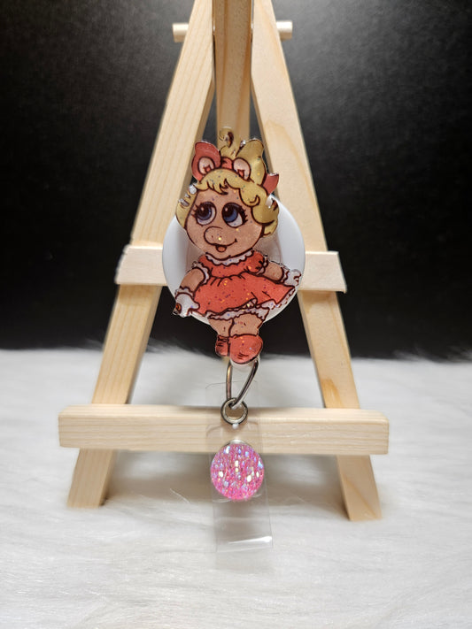 Badge reel with cartoon pig character and dangling pink beaded charm