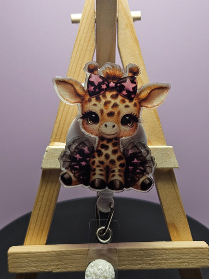 A colorful retractable badge reel featuring a cartoon giraffe with a star pattern on its body, attached to a wooden display stand.