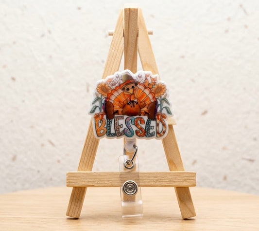 Blessed charm badge with orange floral turkey design and silver clip, on white strap