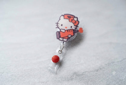 HK badge reel with Hello Kitty figure and red beaded charm, metal loop clasp